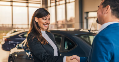 Concessionnaire de voitures souriant serrant la main d’un client dans une salle d’exposition automobile.