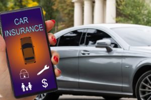 Main de femme tenant un smartphone pour une demande d’assurance auto en ligne.
