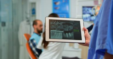 Dentiste tenant une tablette avec une radiographie, patient assis sur un fauteuil