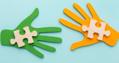 Deux mains découpées en papier, l’une verte et l’autre orange, tenant chacune une pièce de puzzle en bois.