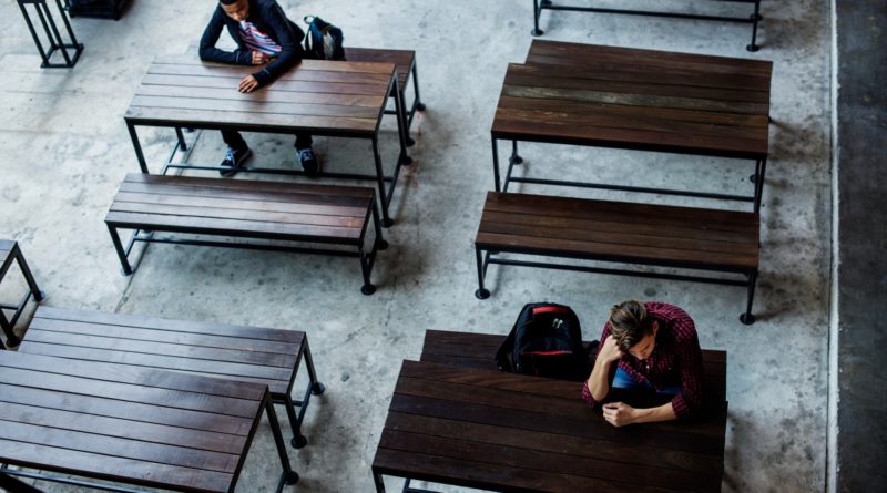 Des adolescents assis seuls dans une cantine vide