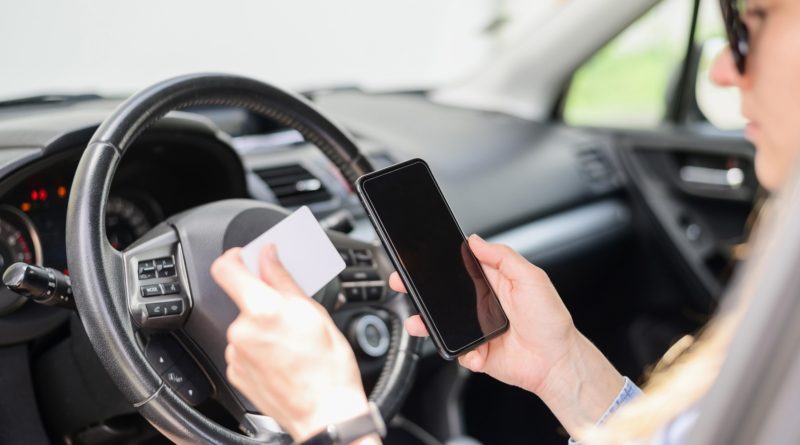 Femme assise dans une voiture tenant un smartphone et une carte
