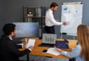 Un homme fait une présentation avec des graphiques devant deux collègues dans une salle de réunion.
