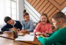 Quatre enfants travaillent ensemble à une table en classe.