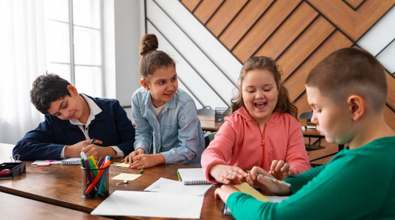 Quatre enfants travaillent ensemble à une table en classe.