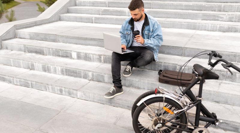 Homme travaillant sur son ordinateur portable à l'extérieur et buvant du café