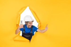 constructeur tenant un pince sur fond jaune