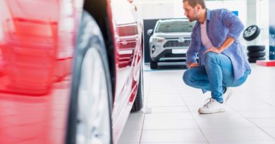 Un homme qui vérifie une voiture rouge