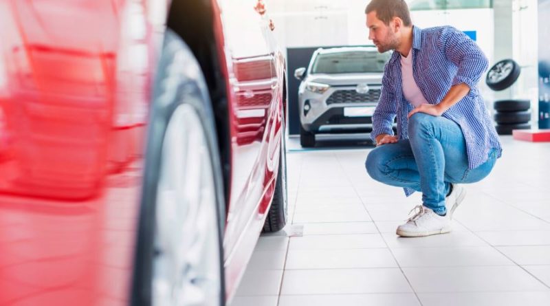 Un homme qui vérifie une voiture rouge