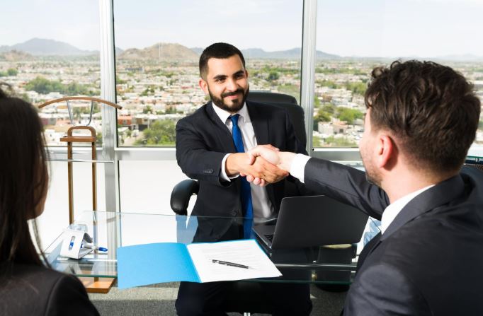 Deux hommes en costume se serrent la main dans un bureau