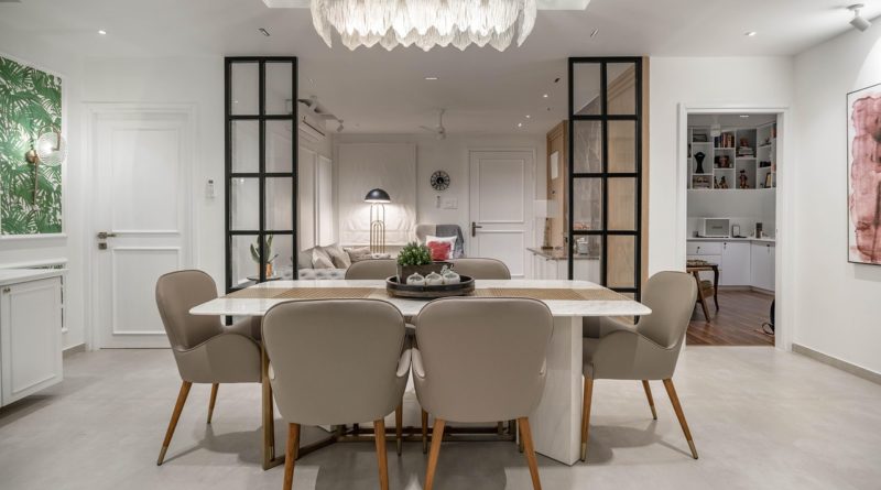 Une grande table en marbre blanc est entourée de six chaises élégantes de couleur taupe avec des pieds en bois et métal