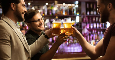 Trois hommes trinquent avec des bières au comptoir d'un bar