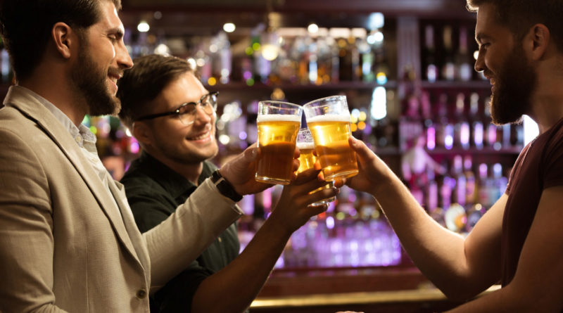 Trois hommes trinquent avec des bières au comptoir d'un bar
