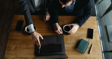 Vue de dessus de deux collaborateurs échangeant autour d'un ordinateur et d'un café