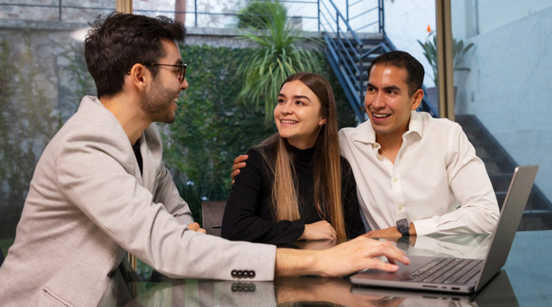 Conseiller indépendant échangeant avec un couple autour d'un laptop.
