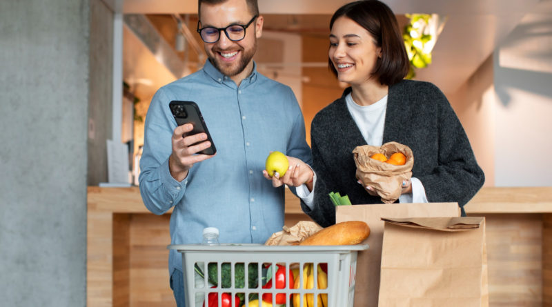 Un jeune couple souriant déballe ses courses de retour du marché