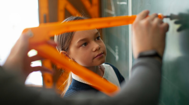 Écolière observant l'utilisation d'un compas géant au tableau