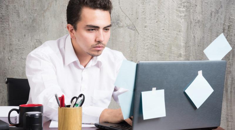 un homme en chemise blanche travaille avec sérieux sur son ordinateur portable