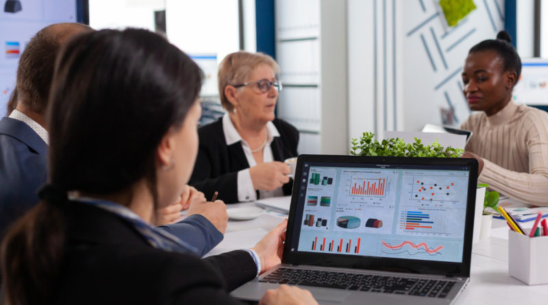 Réunion d'experts analysant des indicateurs financiers sur laptop.