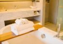 Une pile de serviettes de bain blanches moelleuses posée sur un pont de baignoire en bois, dans une salle de bain de luxe moderne.
