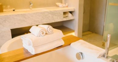 Une pile de serviettes de bain blanches moelleuses posée sur un pont de baignoire en bois, dans une salle de bain de luxe moderne.