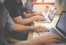 les mains de plusieurs personnes assises en ligne, en train de travailler activement sur leurs ordinateurs portables alignés sur une table de bureau