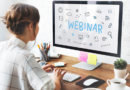 Une femme de dos travaille sur un ordinateur de bureau affichant le mot « WEBINAR » entouré d'illustrations liées à la communication numérique.