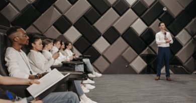 un orateur debout avec un microphone s'adressant à un public attentif assis dans une salle de conférence